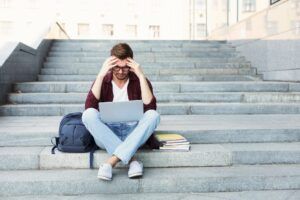 Desperate student sitting on stairs with laptop