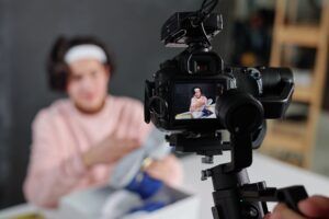 Young vlogger in casualwear showing sneakers on display of digital video camera