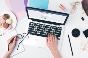 top view of woman using laptop and holding eyeglasses in hand with facebook website