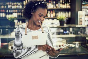 Young African entrepeneur standing in her cafe using a tablet