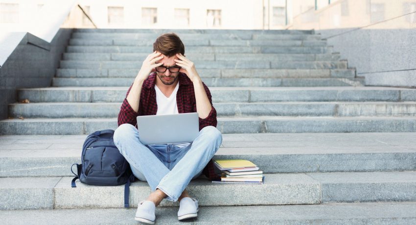 Desperate student sitting on stairs with laptop