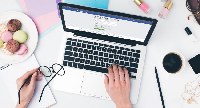 top view of woman using laptop and holding eyeglasses in hand with facebook website