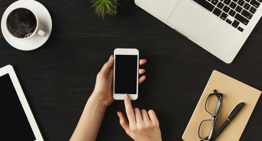 Woman's hands holding a smartphone, top view